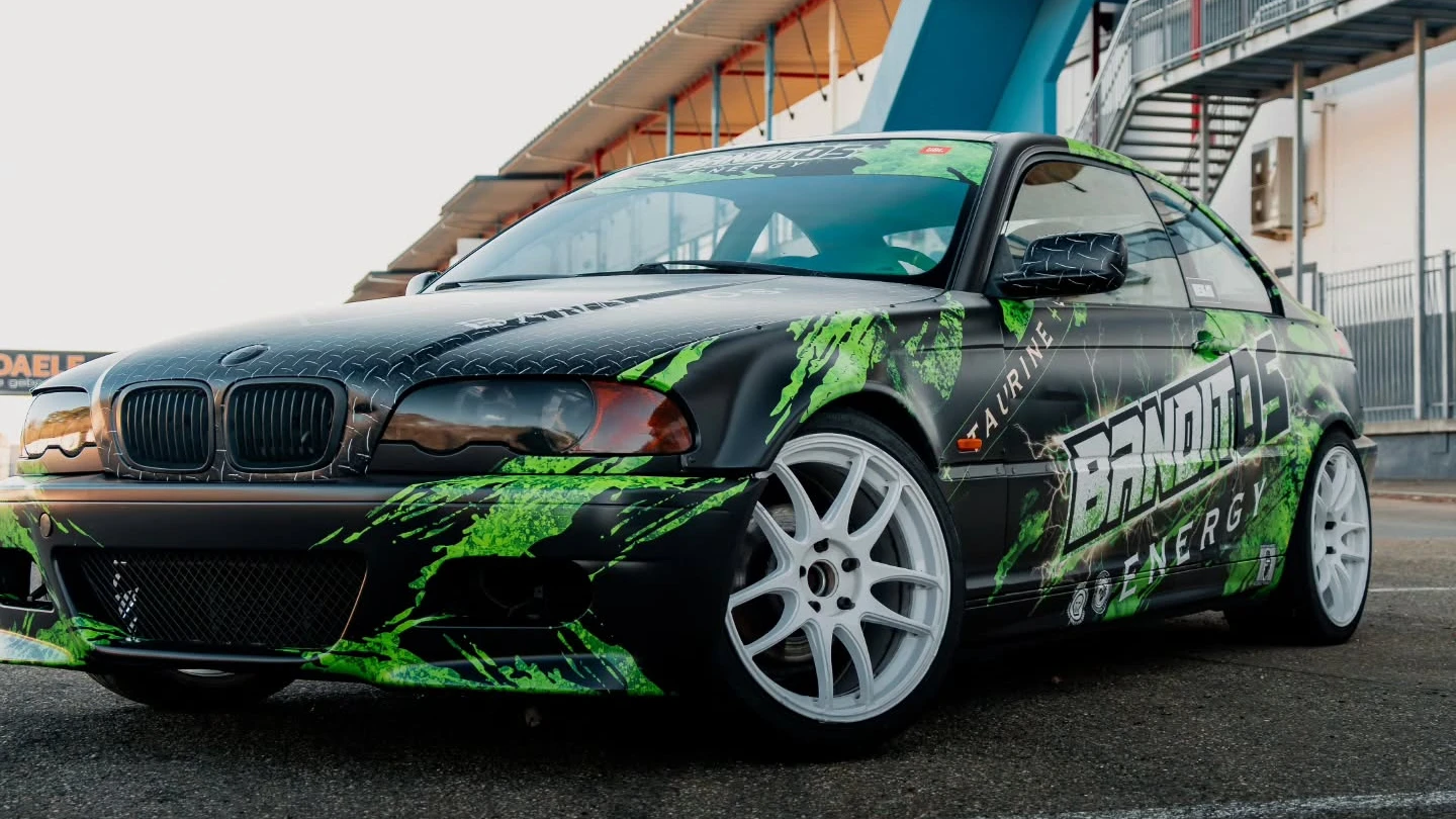 BMW E46 Banditos Energy custom livery wrap — lage driekwart voorkant bij de tribune — FRD × WMR